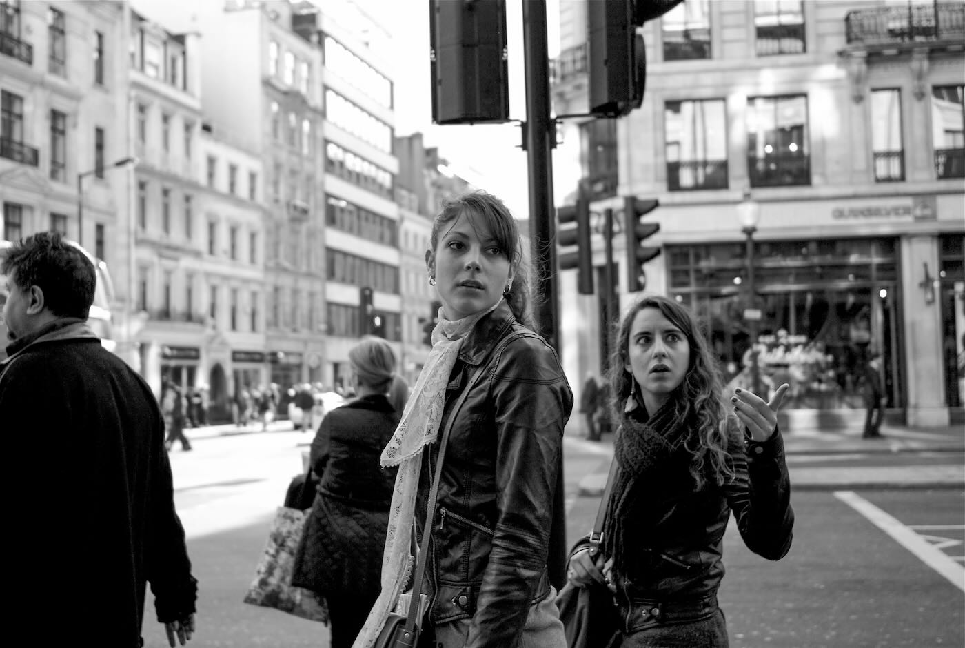 Black and white street photograph of two stylish women window shopping on Oxford Street in London