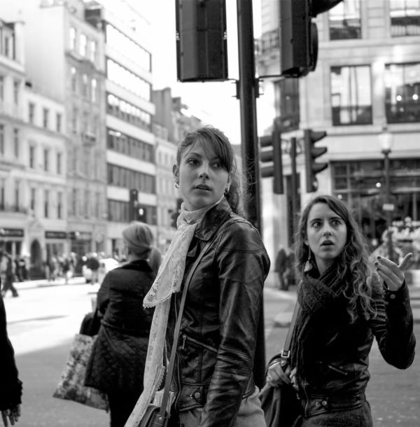 Black and white street photograph of two stylish women window shopping on Oxford Street in London