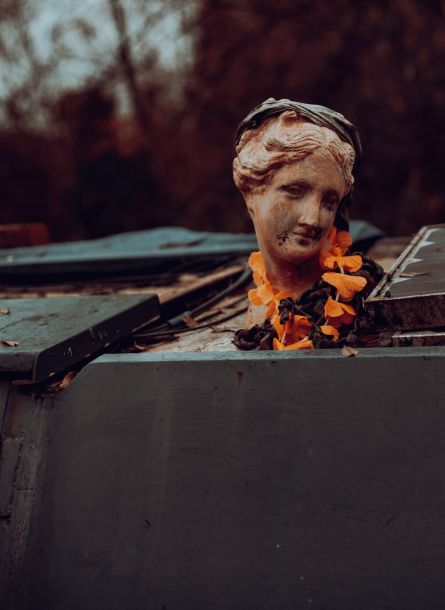 Portrait of a person on a canal boat roof wearing a cap and Hawaiian flowers